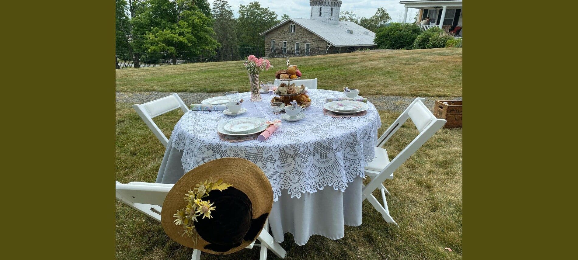 Small table on the lawn with a lace table cloth and pastries.