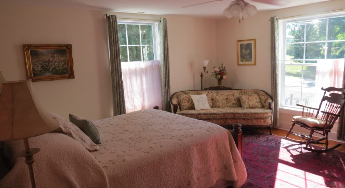 Large Room featuring a queen size bed and antique sofa with sunny window