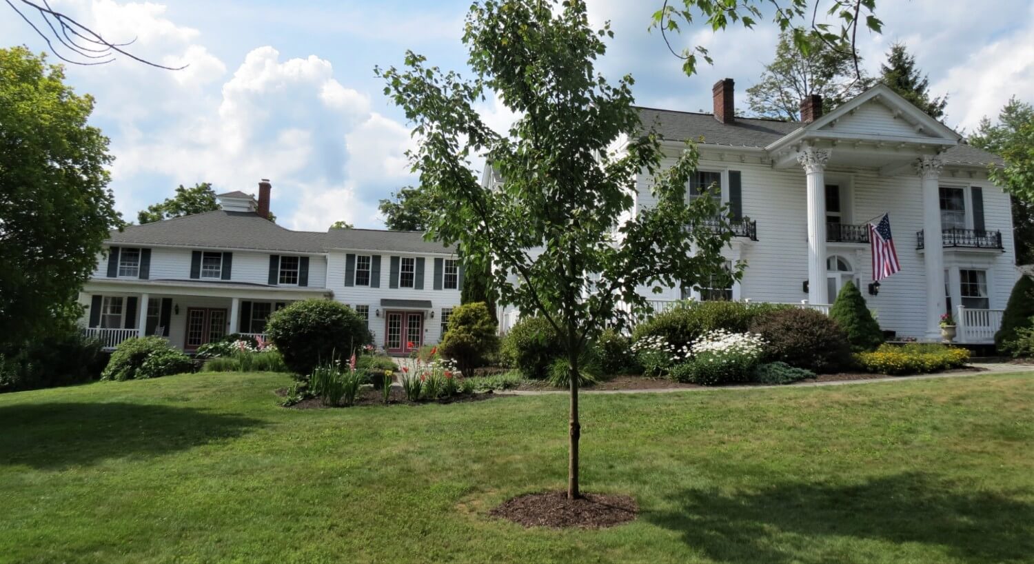 Expansive white home with tall pillars and side view with several windows and peaks