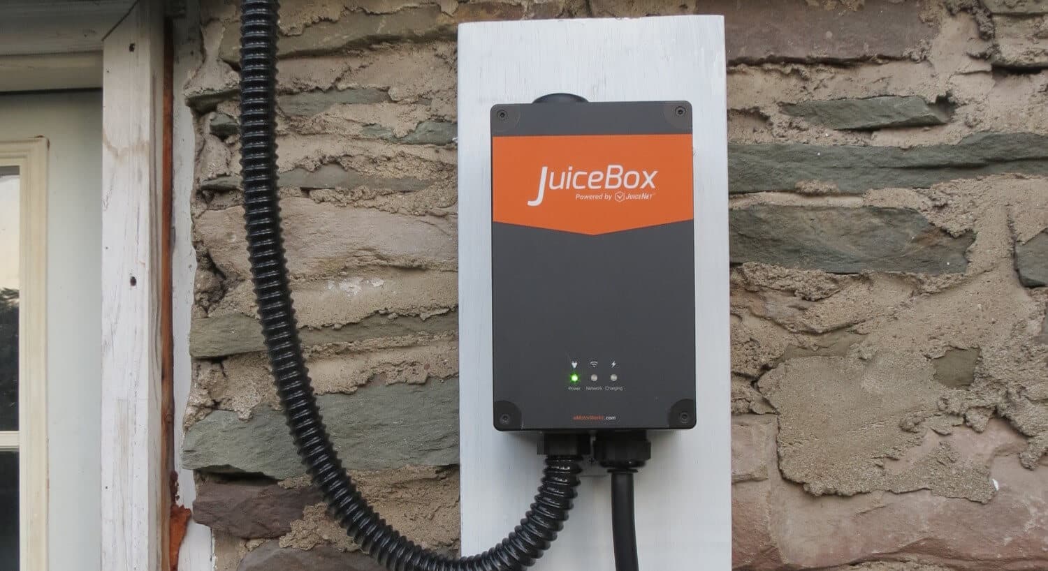 Grey and orange car charging box hanging on a stone wall 