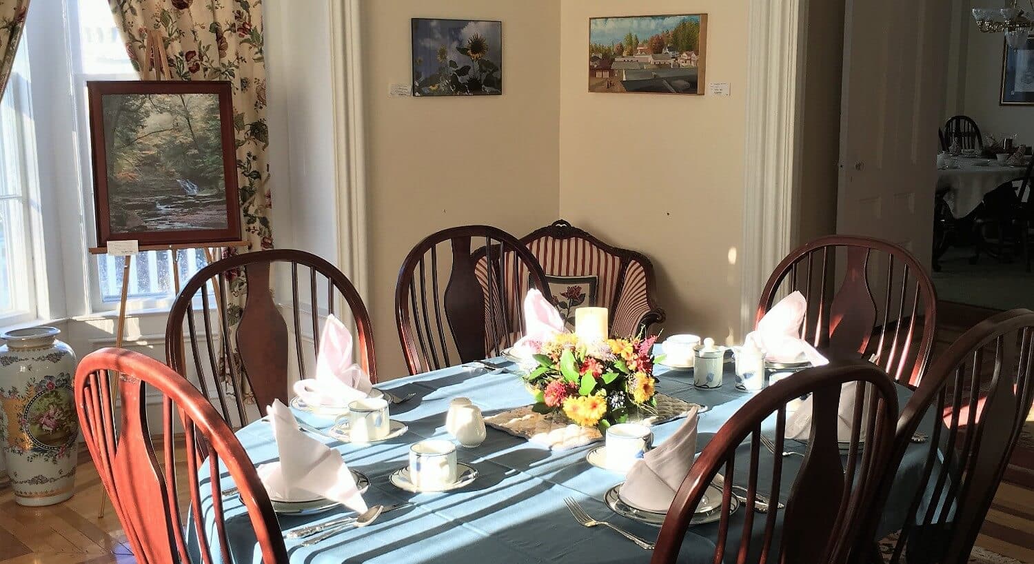 Oval table set for six with tablecloth and napkins in breakfast room. 