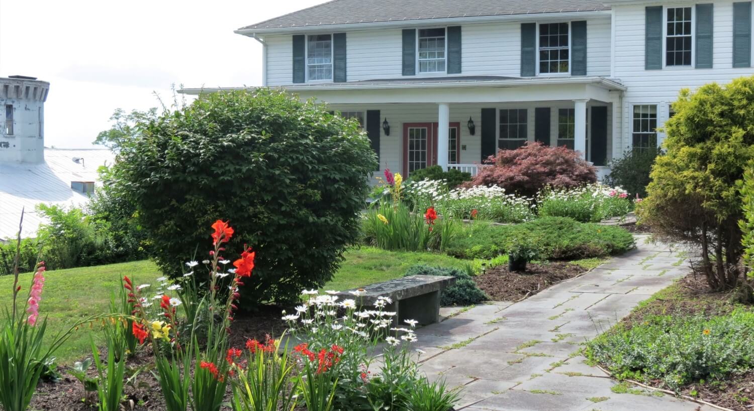 Facade of a white home with a curved sidewalk leading up to a porch with white pillars