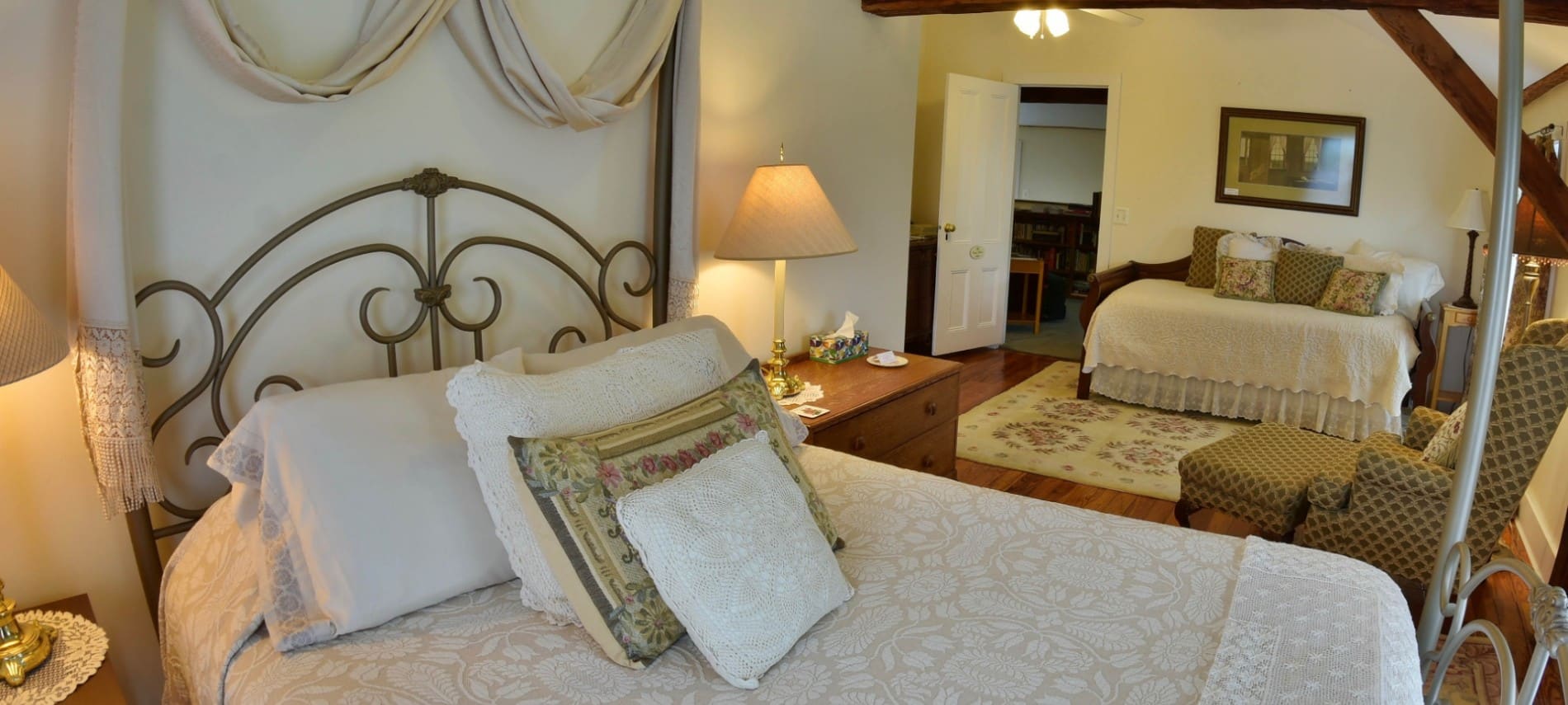 Large guest room with two queen beds, white comforters and wood beams on the ceiling