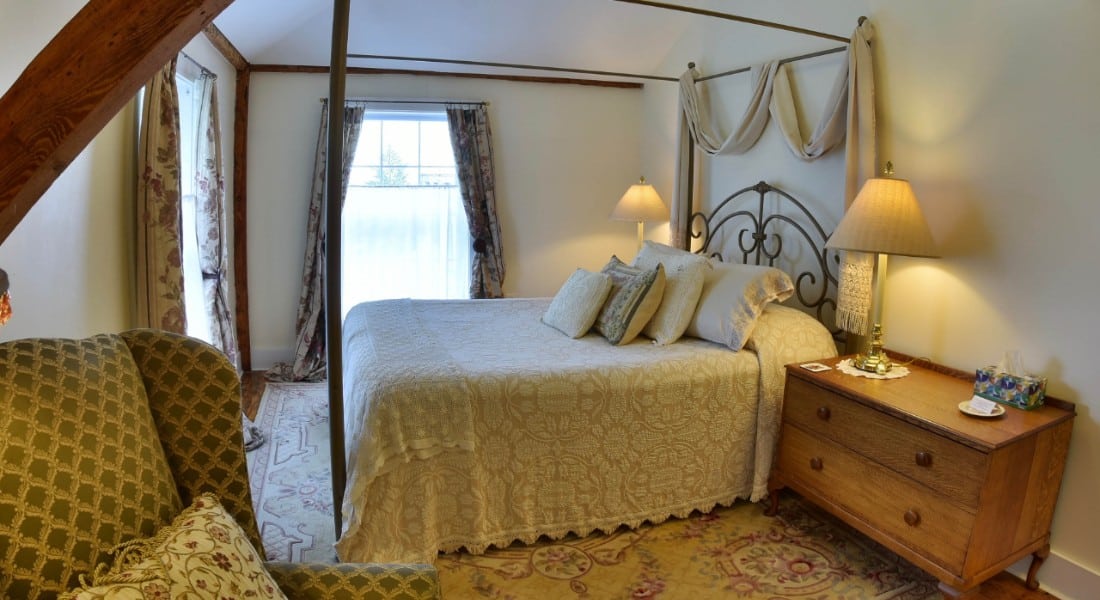 Bright airy bedroom with a large canopy bed, big windows and a persian rug.