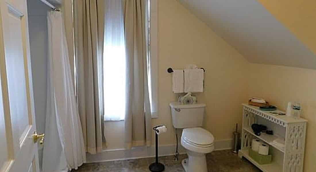 Bathroom painted white with pitched ceiling and white fixtures.